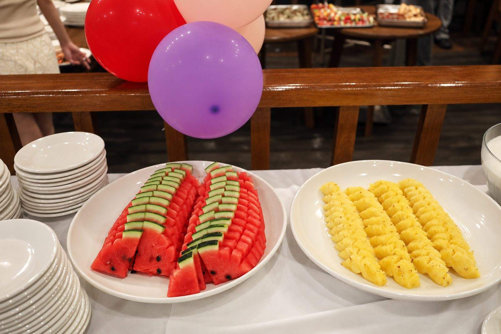 Platters of sliced watermelon and pineapple laid out for a buffet