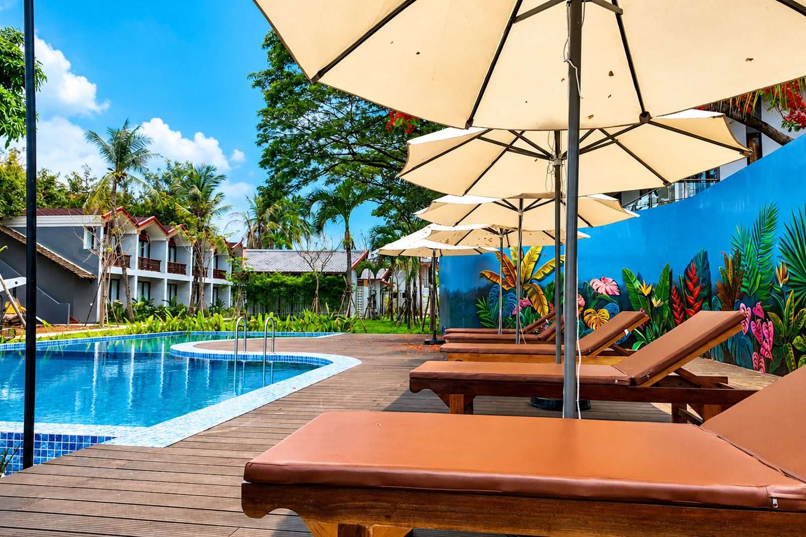 Poolside loungers and parasols beside a painted mural wall